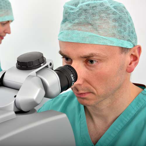 Mr Jonathan Ross looking down a microscope during cataract surgery